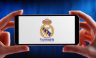 POZNAN, POL - JUN 20, 2020: Hands holding smartphone displaying logo of Real Madrid, a Spanish professional football club based in Madrid