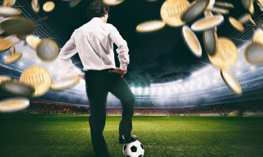 Confident businessman in the center of the soccer field collects a lot of money from the football