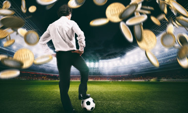 Confident businessman in the center of the soccer field collects a lot of money from the football