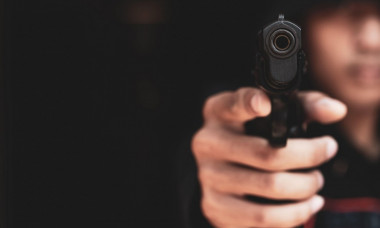 The gangster aimed a gun at the camera. A thief pointing a gun at the target on dark background. selective focus on the front gun, Blurred focus.