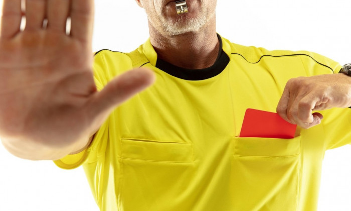 Referee showing a red card to a displeased football or soccer player while gaming isolated on white studio background. Concept of sport, rules violation, controversial issues, obstacles overcoming.