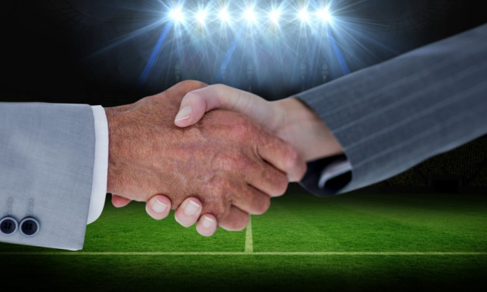 Composition of business people shaking hands over sports stadium