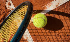 A tennis ball with details of a racquet , shadows and a clay court