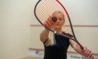 blonde girl holding a racket for squash games.