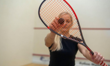 blonde girl holding a racket for squash games.
