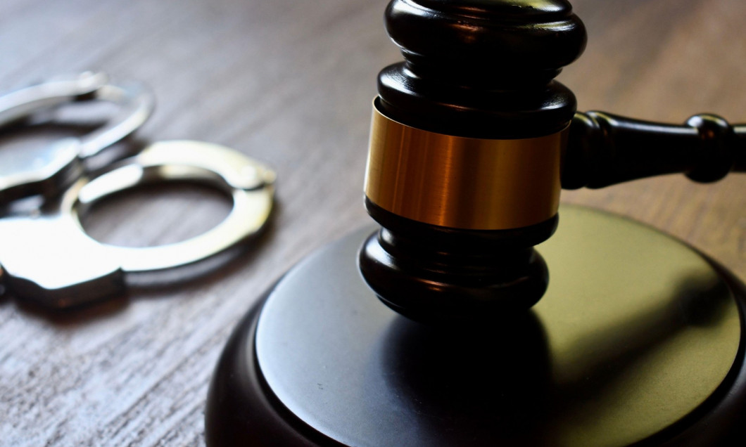 Judges gavel and block with handcuffs on a dark wooden table