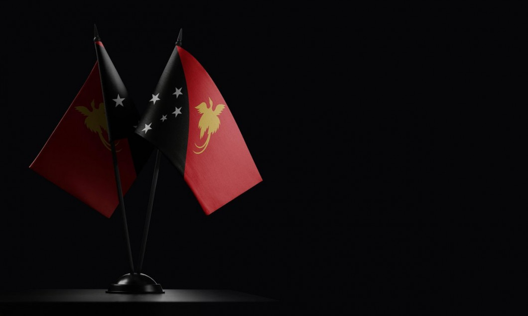 Small national flags of the Papua New Guinea on a black background.