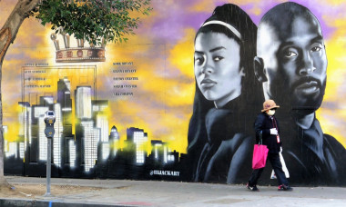 EXCLUSIVE: A Woman wearing a mask walks by Kobe Bryant Mural in Los Angeles as Coronavirus Epidemic Numbers Soar