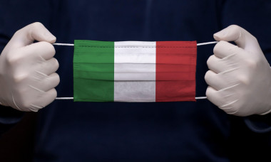 Health employee doctor holding medical face mask with Italy flag. Coronavirus (COVID-19) pandemic affects the country.