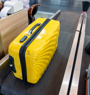 Yellow large luggage on belt at counter airline