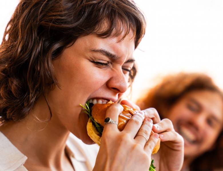 femeie care mananca un burger