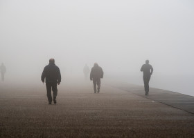 Unrecognizable,People,Walk,Through,Dense,Fog,,At,The,Seafront,Of