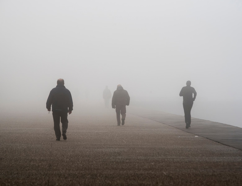 Unrecognizable,People,Walk,Through,Dense,Fog,,At,The,Seafront,Of