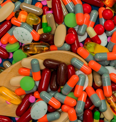 Pile of colorful pills and wood spoon. Medicine, vitamins, supplement and minerals. Antibiotics drug resistance and drug use with reasonable concept.