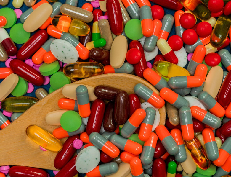 Pile of colorful pills and wood spoon. Medicine, vitamins, supplement and minerals. Antibiotics drug resistance and drug use with reasonable concept.
