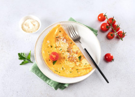 Eggs omelette with cheese, tomato and parsley on a white background. Top view.