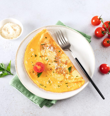 Eggs omelette with cheese, tomato and parsley on a white background. Top view.