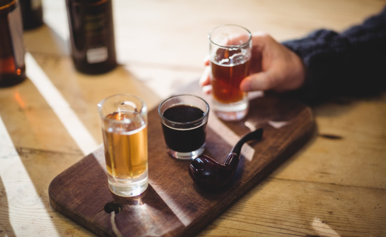 Cropped image of mature man taking a glass of alcohol