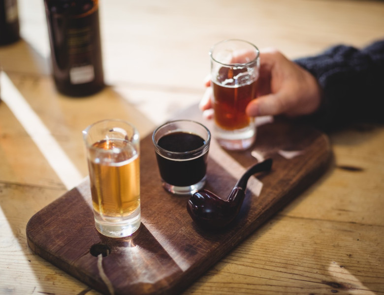 Cropped image of mature man taking a glass of alcohol