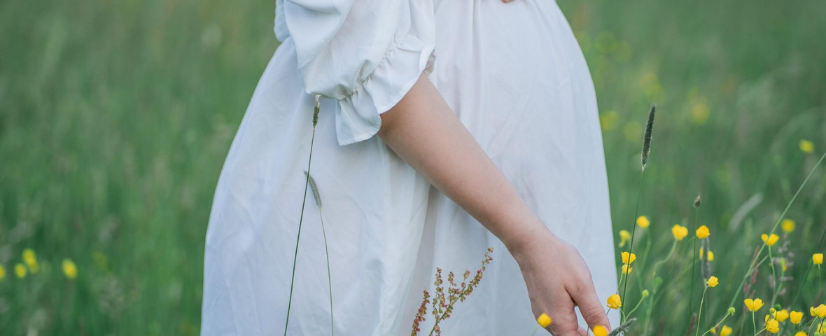 Pregnant young woman holds her hands on her belly, walking in the field in anticipation of the baby. Happy motherhood.