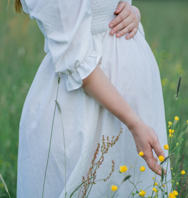 Pregnant young woman holds her hands on her belly, walking in the field in anticipation of the baby. Happy motherhood.