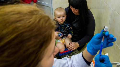 Copil așteptând cu mama să fie vaccinat, imunizare
