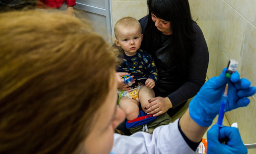 Copil așteptând cu mama să fie vaccinat, imunizare