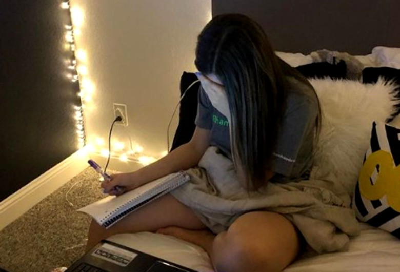 Adolescentă scrie pe caiet