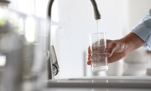 Man,Pouring,Water,Into,Glass,In,Kitchen,,Closeup