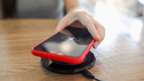 Charging mobile phone battery with wireless device in the table. Smartphone charging on a charging pad. Mobile phone near wirele