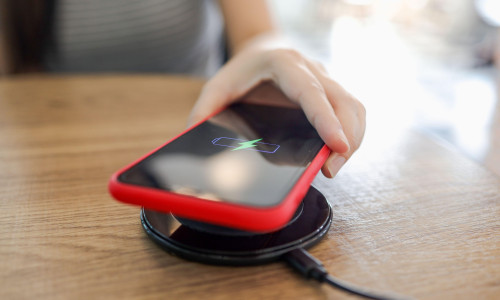 Charging mobile phone battery with wireless device in the table. Smartphone charging on a charging pad. Mobile phone near wirele
