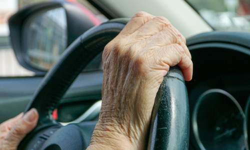 View,Of,Old,Hands,On,A,Car's,Steering,Wheel,,Driving