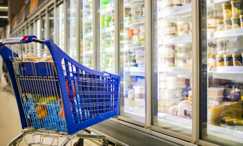 A shopping cart with grocery products in a supermarket