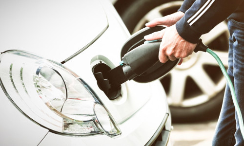 Man charging electric car at charging station