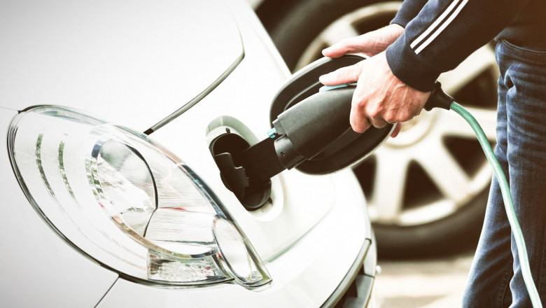 Man charging electric car at charging station