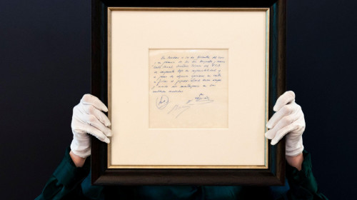 A Bonhams staff member holds up a napkin on which a written commitment was made to Lionel Messi, when he was 13-years-old, for a contract from FC Barcelona in December 2000, on display at Bonhams in London before it is offered at auction. Picture date: We