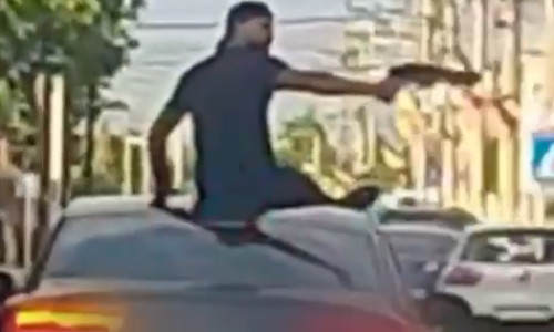 Doi bărbați, urcați pe plafonul unei maşini, au îndreptat o armă către trecători, la Turnu Măgurele/ Foto: News.ro.