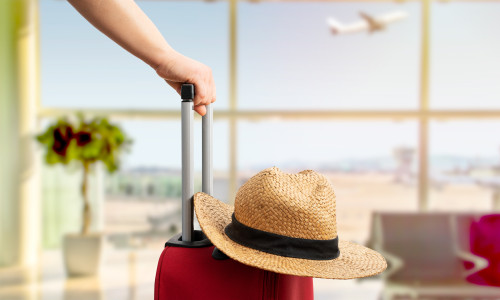 Woman,With,Red,Suitcase,And,Hat,Standing,At,Airport.tourism,Concept