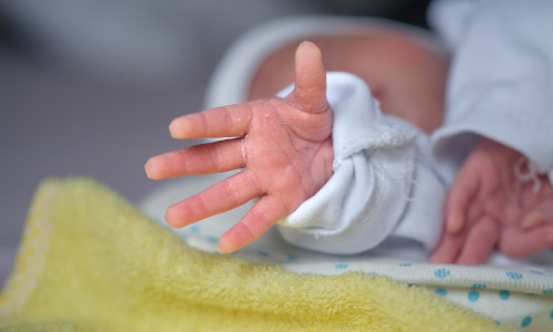 The,Newborn,Baby's,Hand,Reaches,Out,As,If,Trying,To