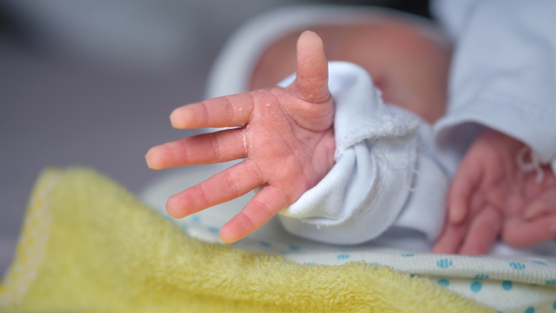 The,Newborn,Baby's,Hand,Reaches,Out,As,If,Trying,To