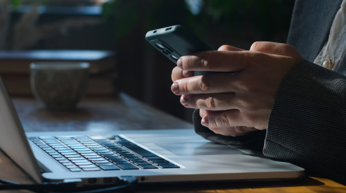 Businesswoman,Uses,Smartphone,Sitting,At,Her,Desk.