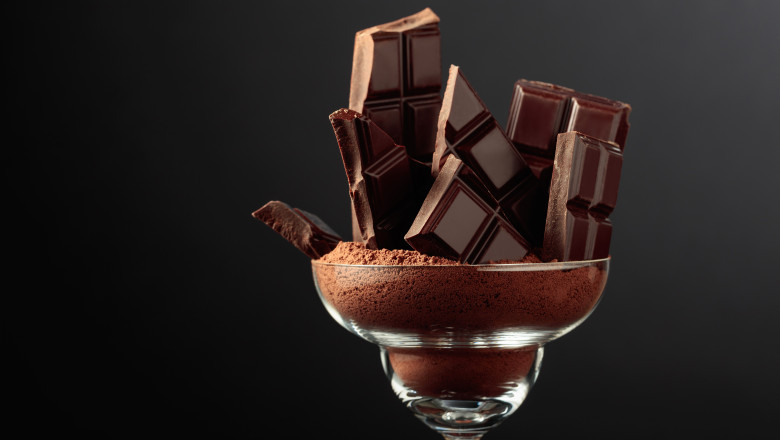 Broken,Black,Chocolate,Bar,In,Glass,With,Cocoa,Powder.,Chocolate