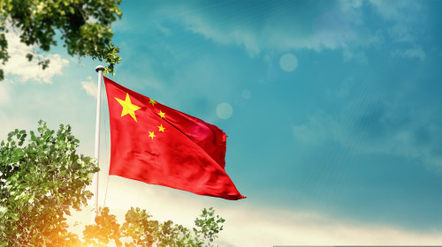 China,National,Flag,Waving,In,The,Sky,Behind,The,Tree.