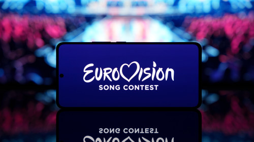 Smartphone,Displaying,Eurovision,Song,Contest,Logo,With,A,Blurred,Stage