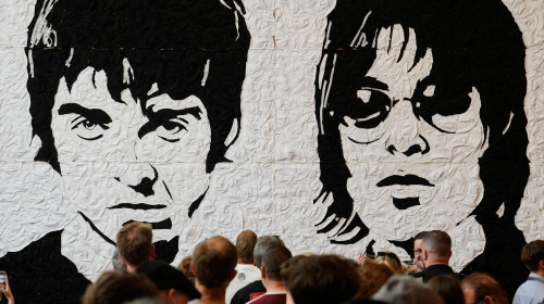 Oasis fans take photos in front of the Wonder Wall - a mural by Welsh artist Nathan Wyburn made out of 3,000 black and white bucket hats depicting Liam and Noel Gallagher - at the St David&apos;s shopping centre in Cardiff, ahead of the first show in the band&apos;