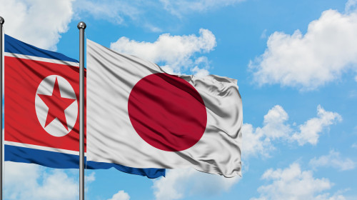 North Korea and Japan flag waving in the wind against white cloudy blue sky together. Diplomacy concept, international relations.
