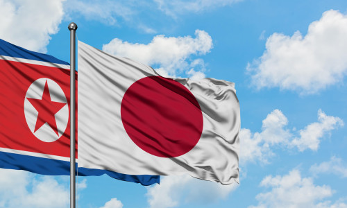North Korea and Japan flag waving in the wind against white cloudy blue sky together. Diplomacy concept, international relations.