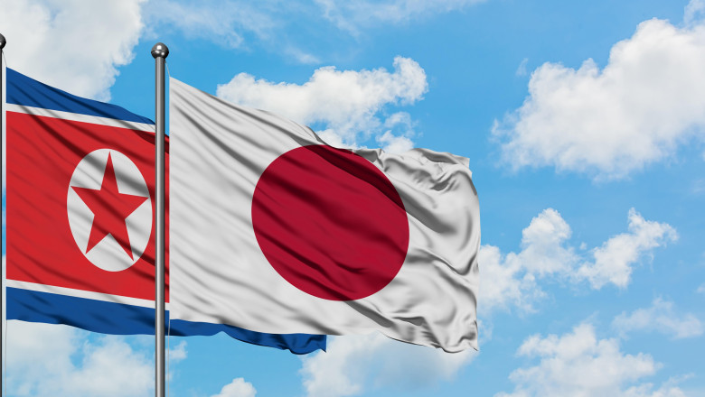 North Korea and Japan flag waving in the wind against white cloudy blue sky together. Diplomacy concept, international relations.
