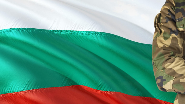 Crossed arms Bulgarian soldier with national waving flag on background - Bulgaria Military theme.