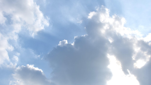 sunlight spreading from dark rain cloud floating on sky in afternoon